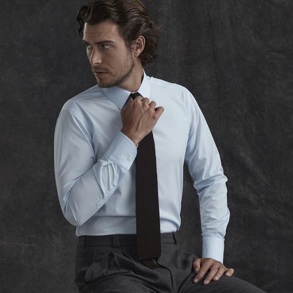 Man adjusting tie with blue business shirt